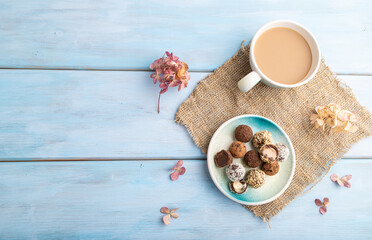 Fototapeta na wymiar Chocolate truffle candies with cup of coffee on a blue wooden background. top view, copy space.
