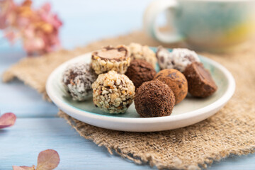Chocolate truffle candies with cup of coffee on a blue wooden background. side view, close up, selective focus.