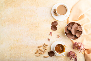 Chocolate chips with cup of coffee on a beige concrete background. top view, copy space.
