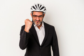 Middle age business man wearing a bike helmet isolated on blue background  showing fist to camera, aggressive facial expression.