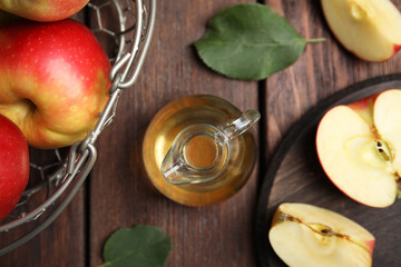 Natural apple vinegar and fresh fruits on wooden table, flat lay