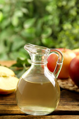 Natural apple vinegar on wooden table against blurred background
