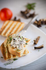 fried bread toast with cheese spread with boiled dried mushrooms on a wooden table.