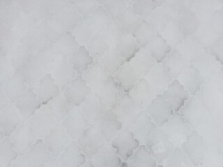 Top view of  tiled walkway snow-covered by the first snow.