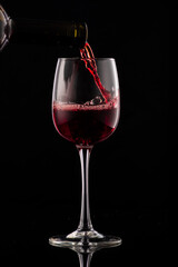 pouring red wine into glass with highlights on red background