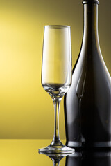 tall champagne glass next to bottle with highlights on yellow background