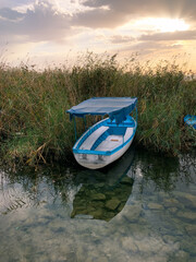 Obraz premium Lonely boat in the reeds on the lake, sunset time