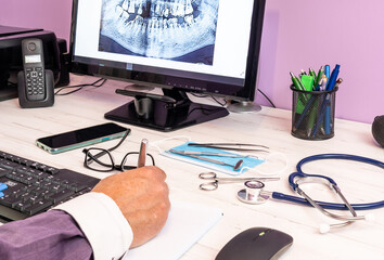medico trabajando en la oficina mirando una radiografia dental en el pc, instrumental medico en la mesa de la clinica - obrazy, fototapety, plakaty