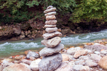 Fototapeta na wymiar Stone pyramid near a fast mountain river. Harmony and balance concept.