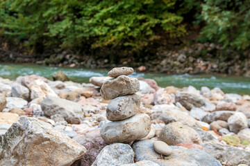 Fototapeta na wymiar The concept of harmony, balance and simplicity. Stone pyramid against the background of a mountain river. Simple balanced pebbles, rock zen