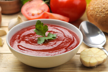 Tomato soup, with herbs and garlic on a natural wooden background. close-up