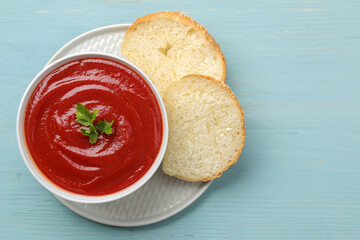 Tomato soup with herbs and bread on a blue wooden table. top view