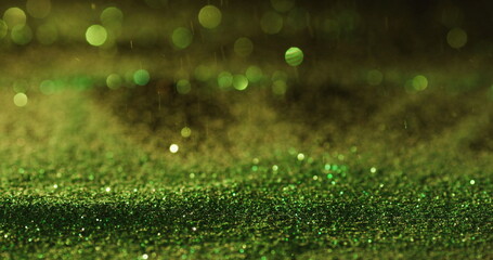 Green glitter gems spilling on black background