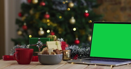 Laptop with green screen on screen, with christmas decorations and tree