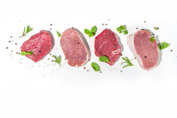 Assorted red meat pieces, raw pork, lamb, beef steaks, portioned meat filet on dark concrete background with spices and herbs for cooking, top view copy space, banner