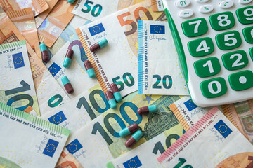 pills with calculator on pile of Euro money as background