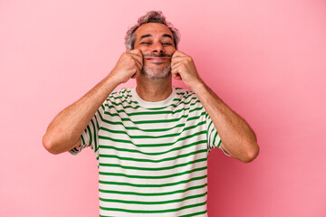 Middle age caucasian man isolated on pink background  doubting between two options.