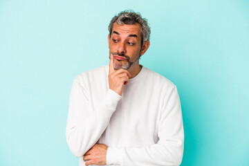 Middle age caucasian man isolated on blue background  looking sideways with doubtful and skeptical expression.