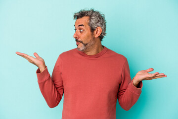Middle age caucasian man isolated on blue background  confused and doubtful shrugging shoulders to...