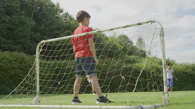 Low Angle Shot Behind Goal Net of Children Playing Football 01