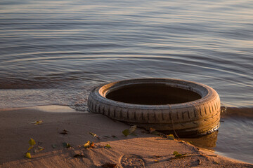Tire abandoned on the beach. Saving the earth. Environmental issue.