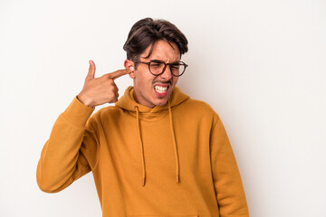 Young mixed race man isolated on white background covering ears with hands.