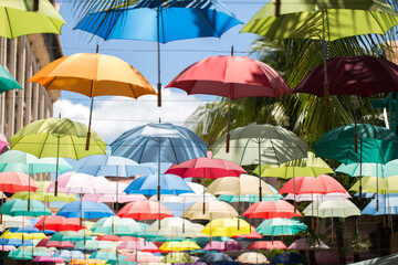 Fototapeta na wymiar Multi-colored umbrellas background. Colorful umbrellas floating above the street. Street decoration.
