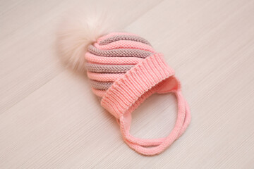 Pink children's knitted wool hat with a pompom, on a white background