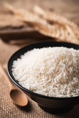 Close up of Organic Thai Jasmine rice grain in a black bowl on brown background