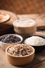 Various Organic Thai rice grain (brown, purple and white rice) in a bowl on brown background