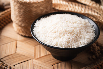 Organic Thai Jasmine rice grain in a black bowl on bamboo tray