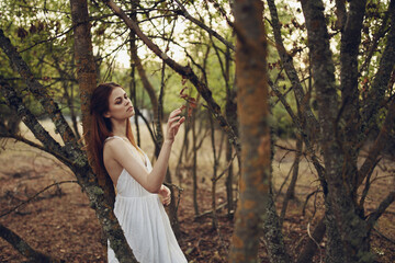 Naklejka na ściany i meble Woman in white dress near trees summer vacation fresh air