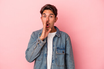 Young mixed race man isolated on white background is saying a secret hot braking news and looking aside