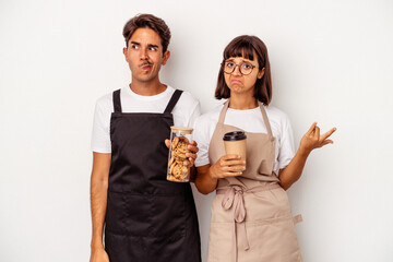 Young mixed race store clerk couple isolated on white background confused, feels doubtful and unsure.