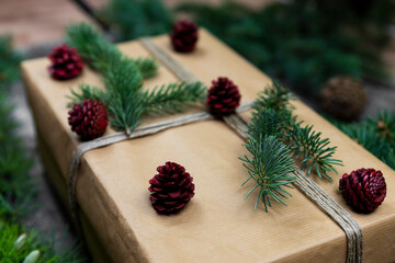 Fototapeta premium Gift box and decoration .Christmas tree branches and pine cones wooden background