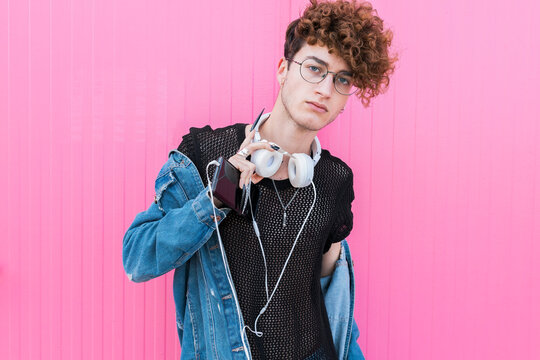 Young gay man wearing eyeglasses in front of pink wall