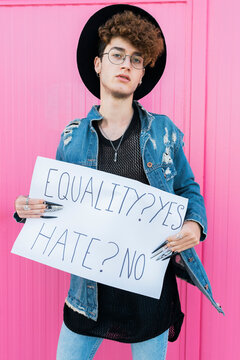 Gay man asking equality standing in front of pink wall