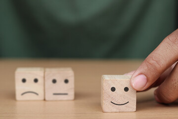 Hand holding wooden cube with smiley face icon, Customer Service Satisfaction Concept