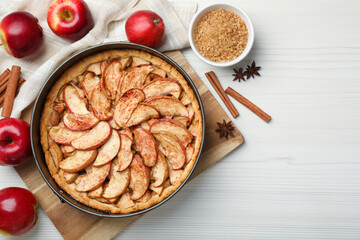 Delicious apple pie and ingredients on white wooden table, flat lay. Space for text
