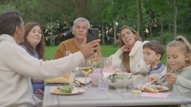 Handheld Shot of Family Talking to Someone Via Phone Video Call During Al Fresco Dinner 02