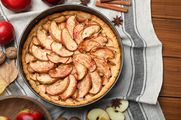Delicious apple pie and ingredients on wooden table, flat lay