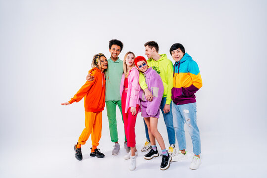 Young men and women in colorful clothes smiling against white background
