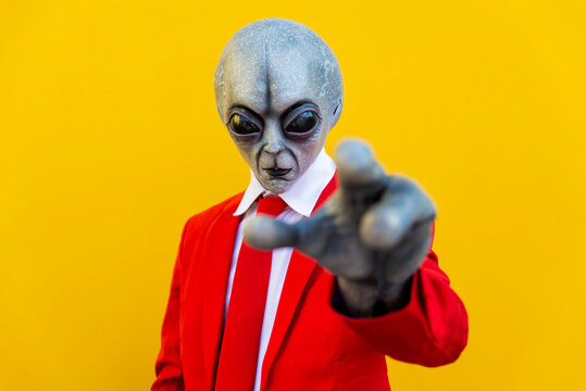 Portrait of man wearing alien costume and bright red suit reaching toward camera