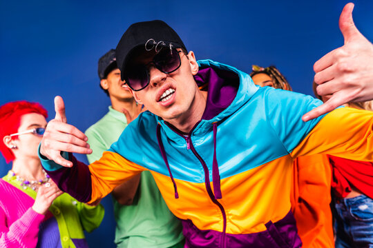 Man gesturing while standing with friends in front of blue background