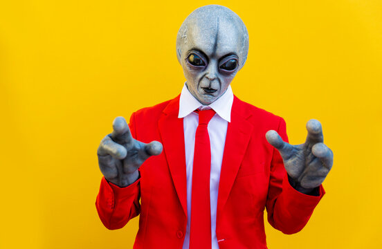 Portrait of man wearing alien costume and bright red suit