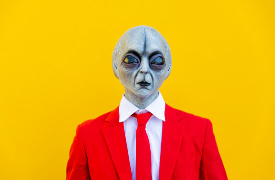 Portrait of man wearing alien costume and bright red suit