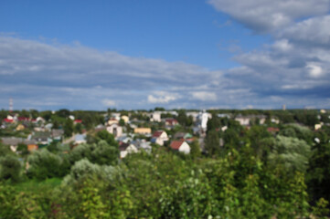 Obraz premium Defocused and blurred background. Panorama of green trees and residential buildings.