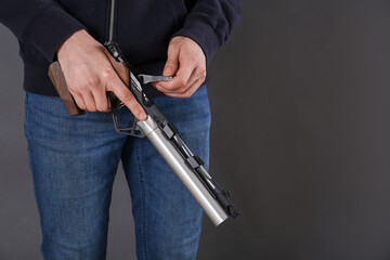 Gun shooting sport. Man holding standard pistol on dark background, closeup. space for text