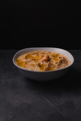 Chickpeas hummus with olive oil and toasted sesame on dark background and selective focus. 