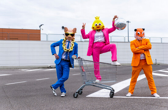 Funny characters wearing animal masks and colored business suits having fun on empty parking lot